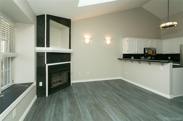 kitchen featuring a large fireplace, baseboards, white cabinets, dark wood-style floors, and dark countertops