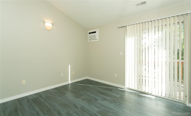 spare room with a wall unit AC, dark wood-style floors, a healthy amount of sunlight, and visible vents