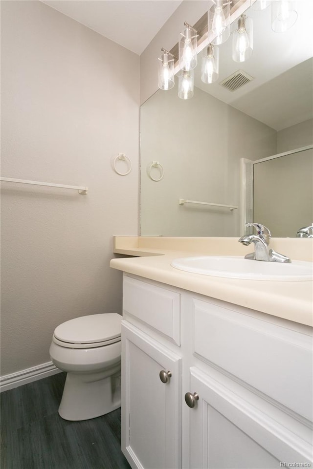 bathroom with toilet, wood finished floors, vanity, visible vents, and an enclosed shower