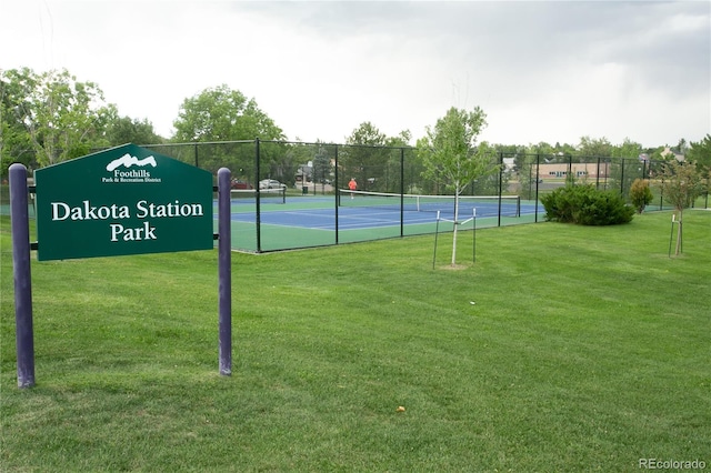 view of tennis court with a yard and fence