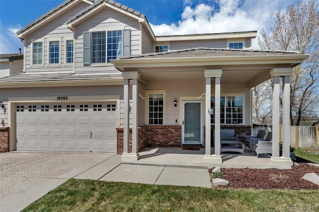 traditional-style home with a porch, concrete driveway, fence, brick siding, and an attached garage