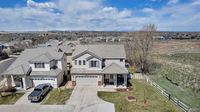 traditional-style home featuring a tile roof, driveway, an attached garage, fence, and a front yard