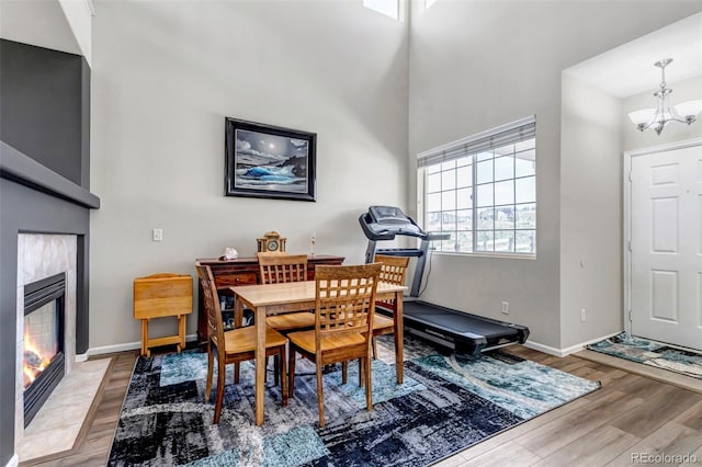dining space featuring light wood finished floors, baseboards, a fireplace, and a notable chandelier
