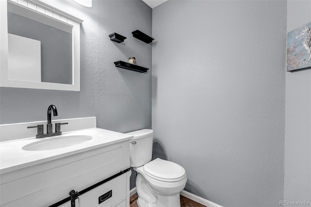 bathroom featuring baseboards, toilet, and vanity