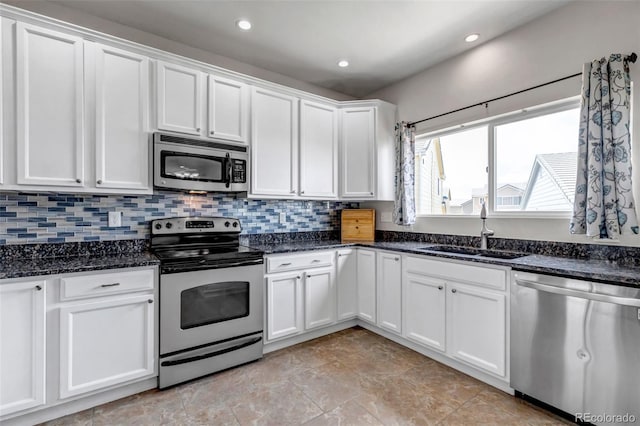 kitchen with dark stone counters, a sink, white cabinetry, backsplash, and appliances with stainless steel finishes