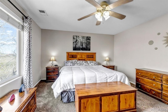 carpeted bedroom featuring baseboards, a ceiling fan, visible vents, and multiple windows