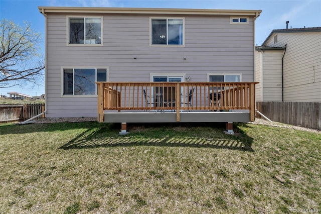 rear view of house featuring a fenced backyard, a wooden deck, and a lawn