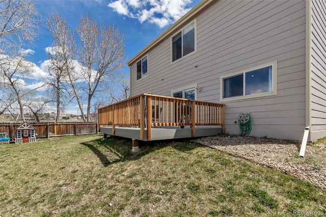 rear view of property featuring a wooden deck, a lawn, and fence
