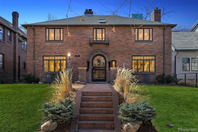 view of front facade with a chimney, a front lawn, and brick siding