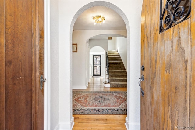 foyer entrance with stairs, a textured wall, wood finished floors, and baseboards