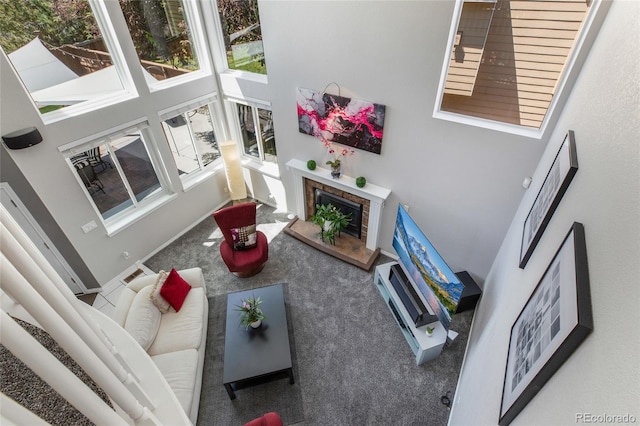 carpeted living area with a fireplace with raised hearth and a towering ceiling