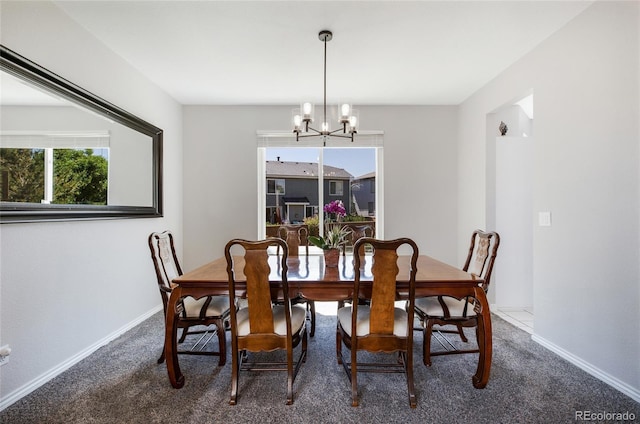 dining space featuring an inviting chandelier, baseboards, and dark carpet