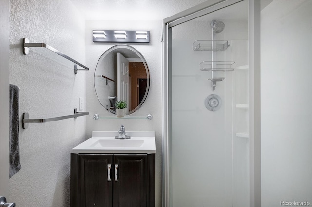 bathroom featuring a shower stall, vanity, and a textured wall