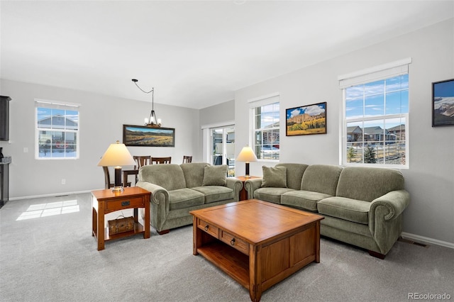 living area with visible vents, light carpet, a notable chandelier, and baseboards