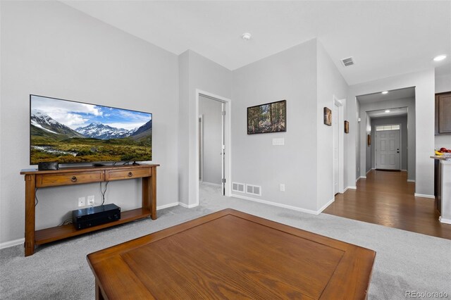 carpeted living area featuring baseboards and visible vents