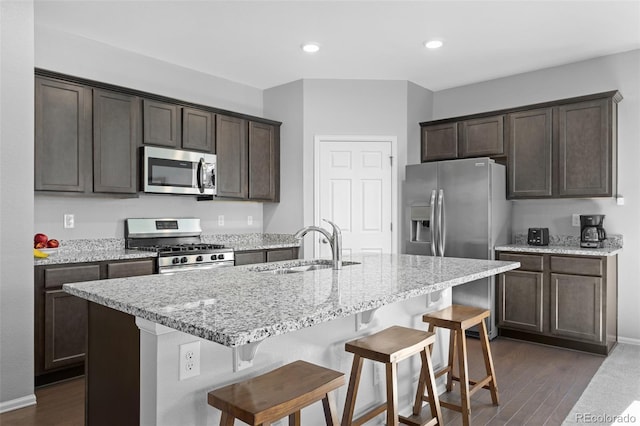 kitchen with dark wood-style flooring, dark brown cabinets, stainless steel appliances, and a sink