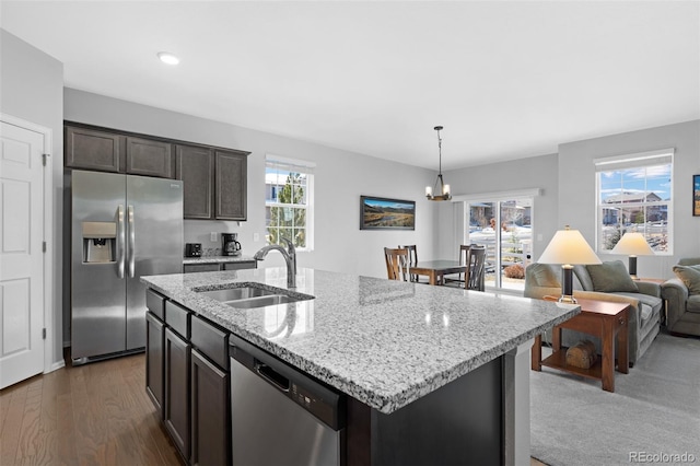 kitchen with a wealth of natural light, appliances with stainless steel finishes, light stone countertops, and a sink