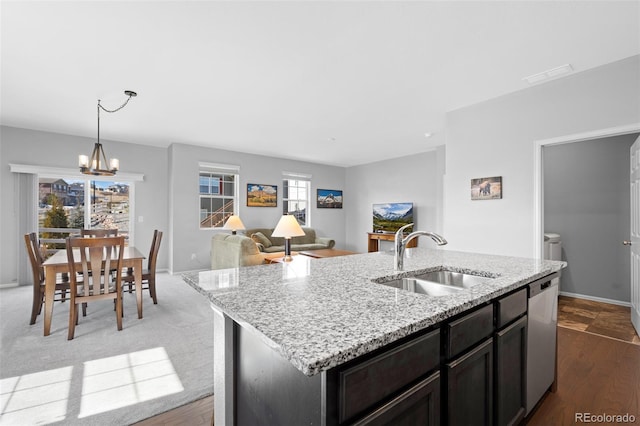 kitchen featuring a sink, stainless steel dishwasher, light stone countertops, a chandelier, and hanging light fixtures