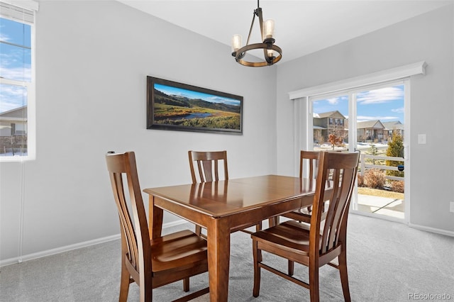 dining space with light carpet, a chandelier, and baseboards