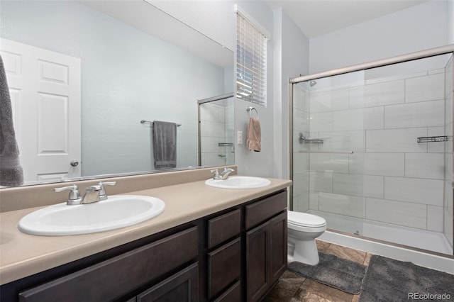 full bathroom with double vanity, toilet, a stall shower, and a sink