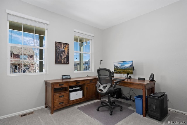 home office with a wealth of natural light, visible vents, light carpet, and baseboards