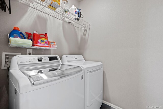 washroom featuring laundry area, separate washer and dryer, and baseboards