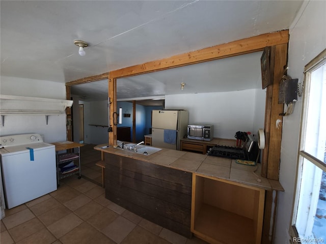 kitchen featuring washer / clothes dryer, white fridge, sink, tile countertops, and light tile patterned flooring