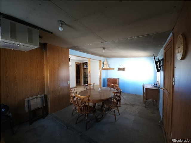 dining room featuring concrete floors and wooden walls