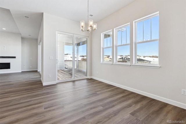 unfurnished dining area with plenty of natural light, a notable chandelier, and dark hardwood / wood-style flooring