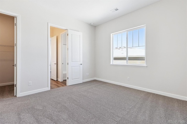 unfurnished bedroom with a walk in closet, light carpet, and a closet