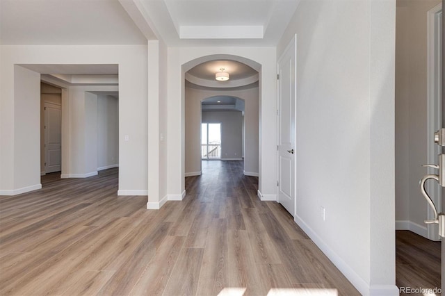 hall featuring a raised ceiling and light hardwood / wood-style floors