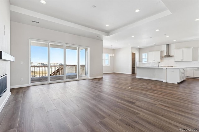 unfurnished living room with dark wood-type flooring and a tray ceiling