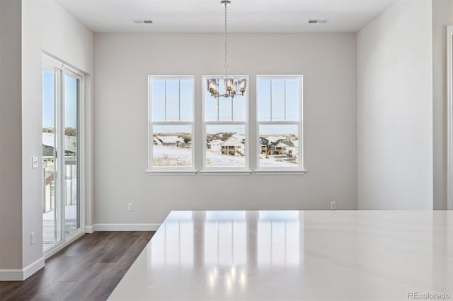 unfurnished dining area featuring an inviting chandelier and dark hardwood / wood-style flooring