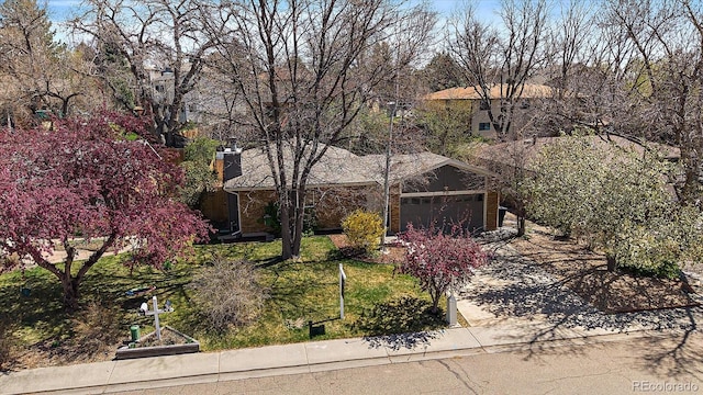 obstructed view of property with concrete driveway, a front yard, and an attached garage