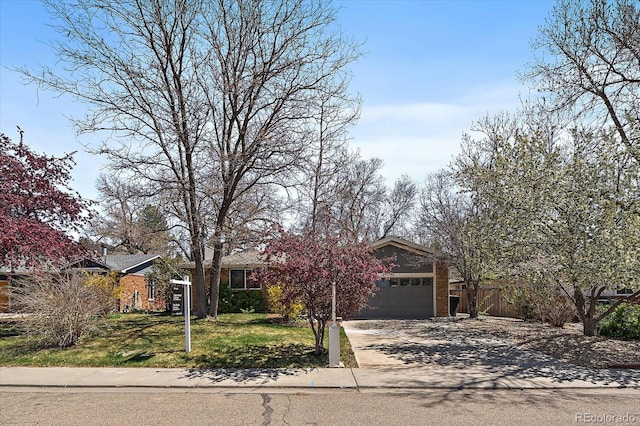 view of property hidden behind natural elements featuring a front yard, driveway, and a garage
