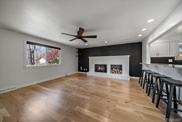 living area featuring light wood-type flooring, a ceiling fan, visible vents, recessed lighting, and baseboards