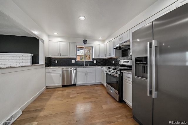 kitchen with visible vents, a sink, appliances with stainless steel finishes, under cabinet range hood, and decorative backsplash