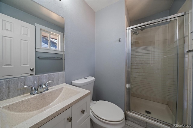 bathroom featuring toilet, a stall shower, and vanity
