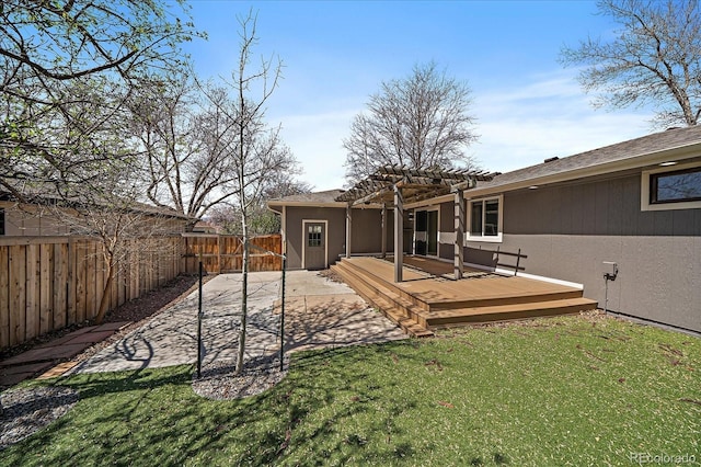 rear view of house featuring a pergola, a wooden deck, a fenced backyard, stucco siding, and a lawn