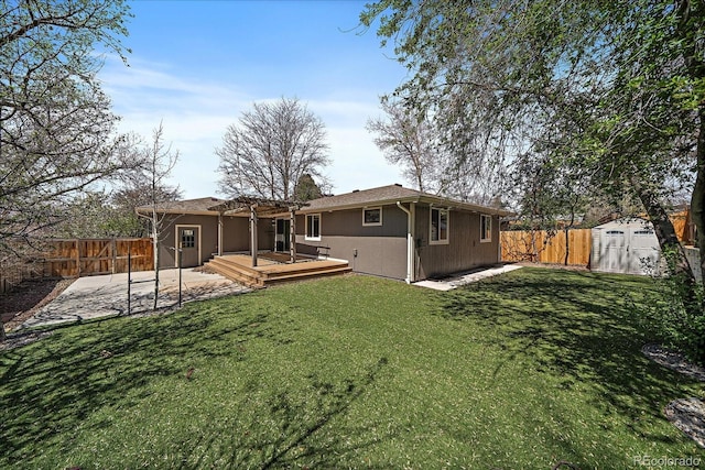 back of house featuring a yard, an outdoor structure, a fenced backyard, and a wooden deck