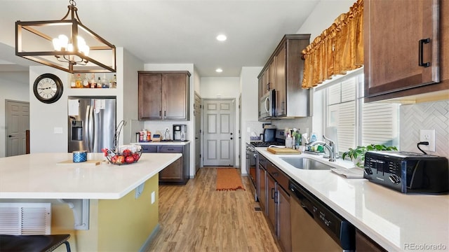 6207 Kildare Dr, Colorado Springs, CO 80927 - kitchen featuring appliances with stainless steel finishes, a sink, tasteful backsplash, light wood-style floors, and light countertops