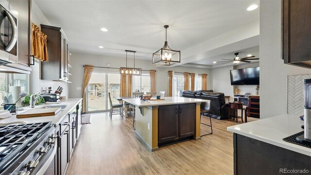6207 Kildare Dr, Colorado Springs, CO 80927 - kitchen with a kitchen breakfast bar, light wood-type flooring, dark brown cabinets, light countertops, and recessed lighting