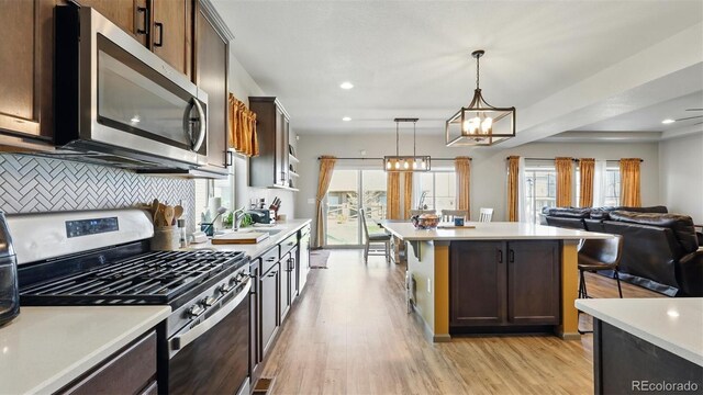 6207 Kildare Dr, Colorado Springs, CO 80927 - kitchen with stainless steel appliances, light countertops, backsplash, light wood-style flooring, and a chandelier