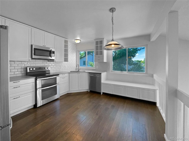 kitchen featuring decorative backsplash, stainless steel appliances, sink, pendant lighting, and white cabinetry