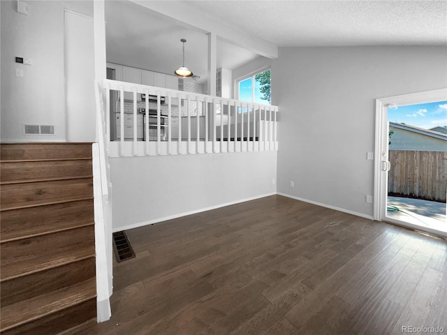 unfurnished room with a textured ceiling, lofted ceiling with beams, and dark hardwood / wood-style floors