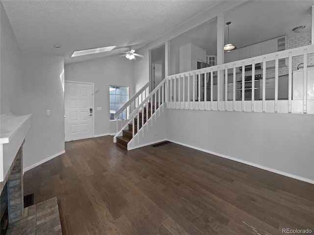 interior space featuring a textured ceiling, dark hardwood / wood-style floors, ceiling fan, and vaulted ceiling with skylight