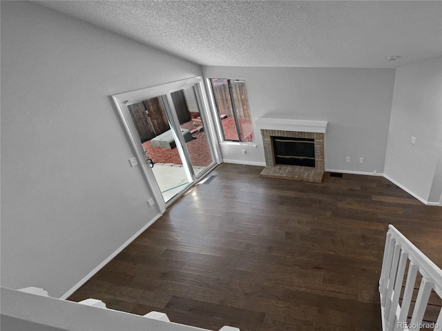 unfurnished living room with a fireplace, dark hardwood / wood-style flooring, and a textured ceiling