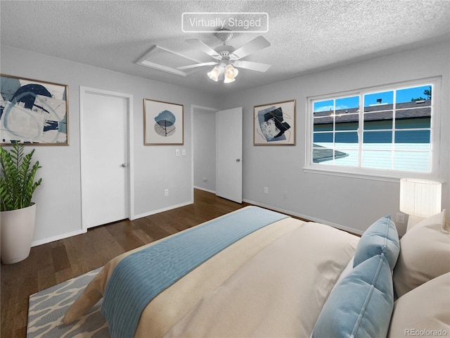 bedroom with ceiling fan, dark hardwood / wood-style floors, and a textured ceiling