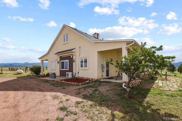 rear view of house with a mountain view, a rural view, ac unit, and a patio area