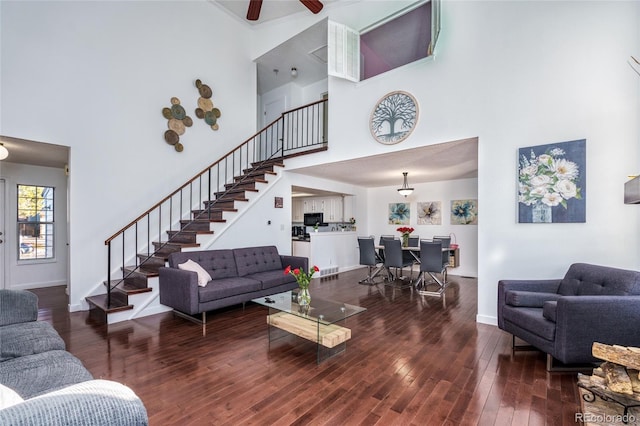 living area featuring a towering ceiling, baseboards, stairway, and hardwood / wood-style floors